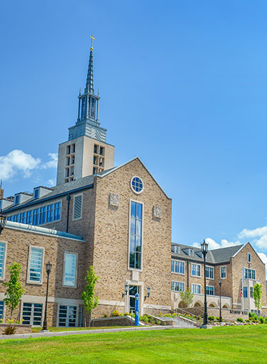 A hawk flies from the spire of Kearney Hall