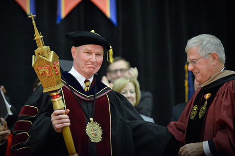 University President Rooney is seen shaking hands with another official during his Inauguration Ceremony.