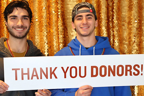 Two Fisher students hold a sign that says Thank You Donors, expressing gratitude for contributions to the Fisher Forward campaign.