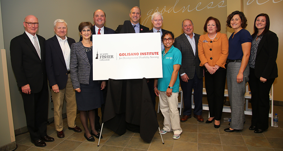 A group of community members pose with Gerry Rooney and Dianne Cooney Miner around a logo for the newly created Golisano Institute for Developmental Disability Nursing.