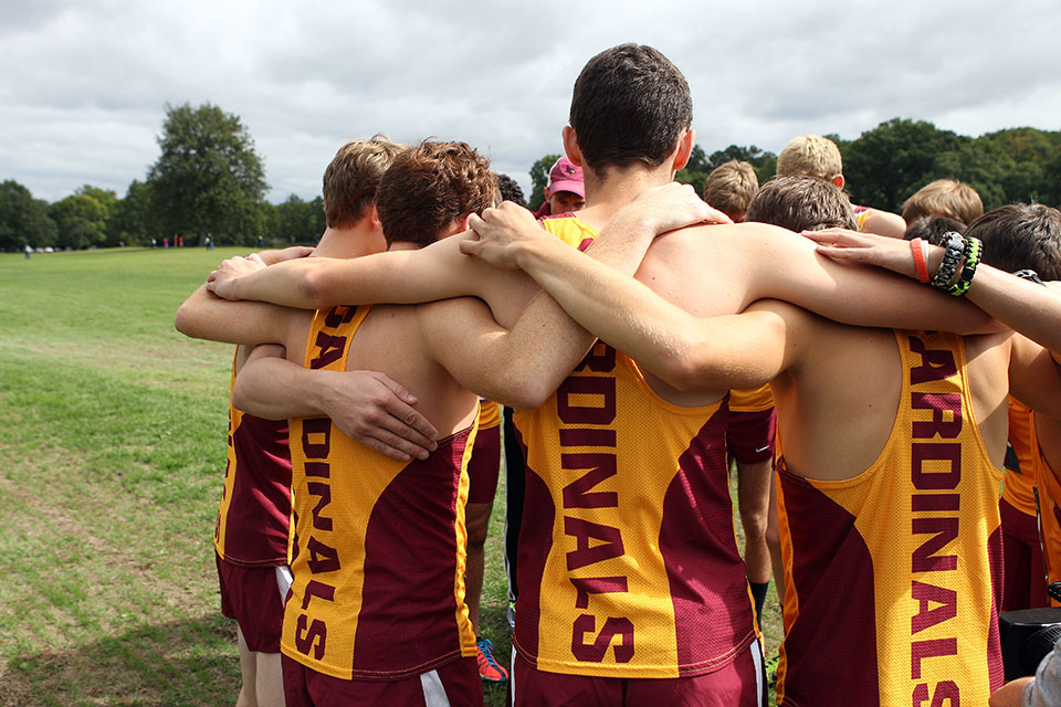 Members of the cross country embrace in a circle.