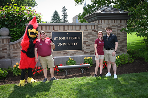 Students and Cardinal pose in front of the new St. John Fisher University sign in July 2022